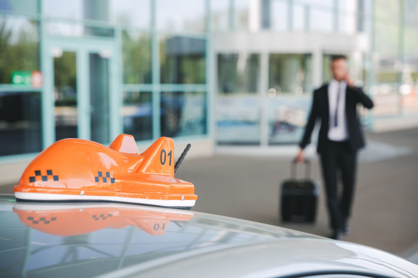 Businessman with rolling luggage arriving at airport for taxi pickup