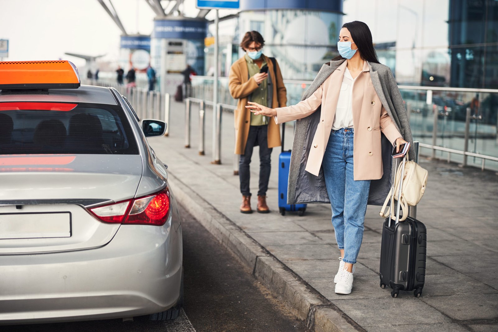 Woman with luggage being greeted curbside at airport for premium pickup